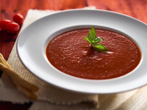 a bowl of tomato soup with a green leaf on top at ibis Coimbatore City Centre - An Accor Brand in Coimbatore