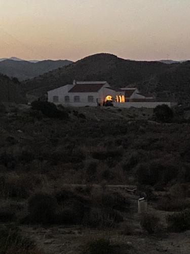 a white barn with a building in the middle of a field at Casa YAJOKE in El Arroyo Aceituno