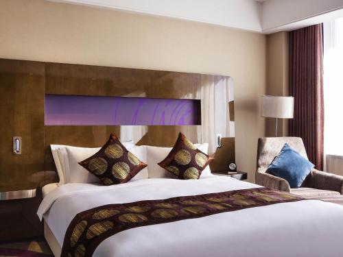a hotel room with a large bed and a chair at Novotel Daqing Haofang in Daqing