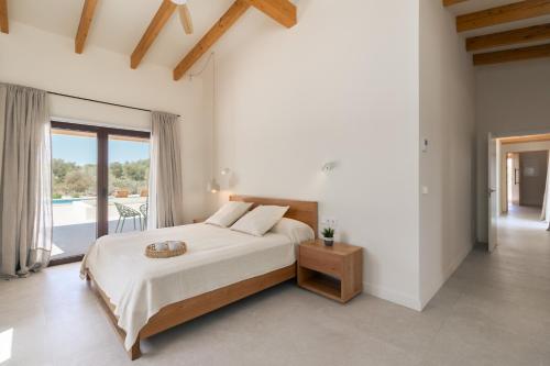 a white bedroom with a bed and a balcony at Villa Olivo in Ses Salines