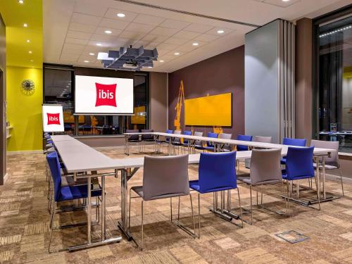Una sala de conferencias con una mesa y sillas y una pantalla. en Ibis Gdansk Stare Miasto, en Gdansk