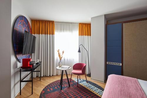 a hotel room with a bed and a pink chair at Hotel Indigo Barcelona Plaza Espana by IHG in Barcelona