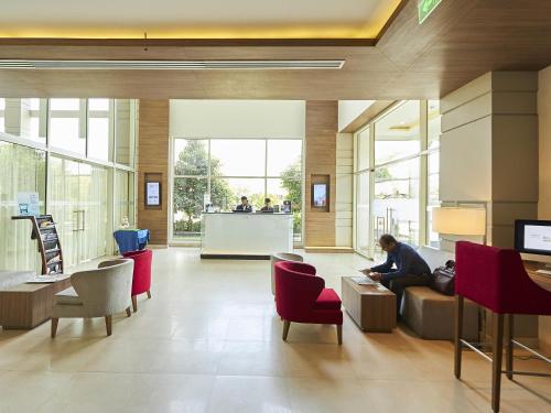 a man sitting on a couch in a lobby at Mercure Chennai Sriperumbudur in Sriperumbudur