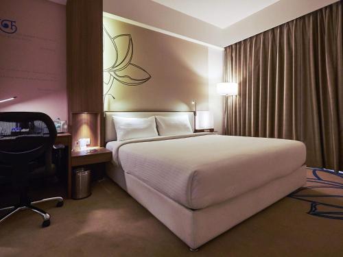 a hotel room with a large bed and a desk at Mercure Chennai Sriperumbudur in Sriperumbudur