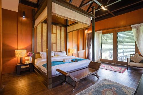 ein Schlafzimmer mit einem Himmelbett und einem Holzboden in der Unterkunft The Langit Duyong Marina Resort in Kuala Terengganu