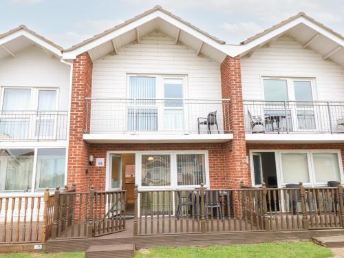 a brick house with a deck and patio at 19 Waterside Park in Lowestoft
