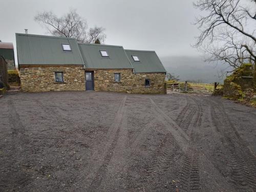 a stone building with a green roof on a dirt road at Aghavannagh Mountain Lodge in Aghavannagh