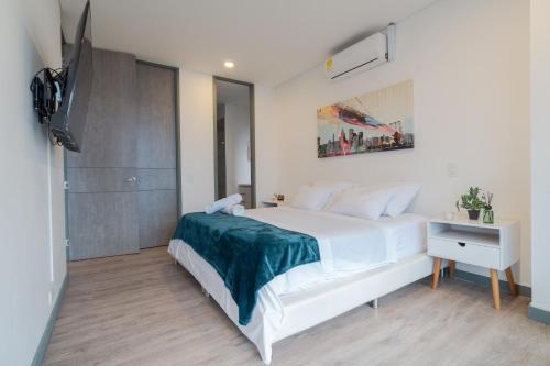 a bedroom with a white bed and a television at CLASS Suites in Medellín