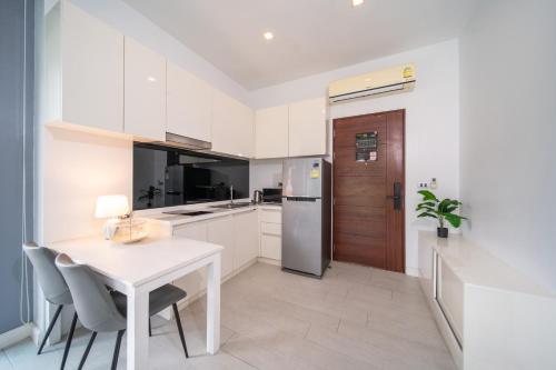 a white kitchen with a table and a refrigerator at 九雅集 The Nine Refined Retreats in Rawai Beach