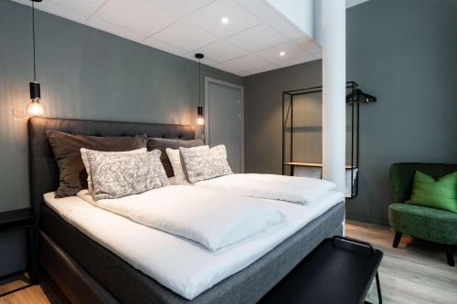 a large bed in a room with a green chair at Scandic Hell in Hell