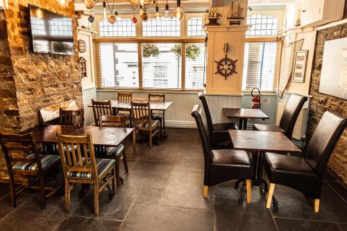 a restaurant with wooden tables and chairs and windows at The Wayfarer Inn in Instow