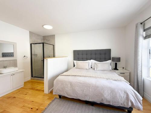 a white bedroom with a bed and a sink at The Bucket List Guest House in Bredasdorp