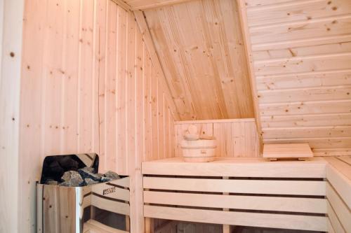 a wooden sauna with a bench and a bucket at Lillebror Skandinavische Ruhe mit privater Sauna in Baden-Baden