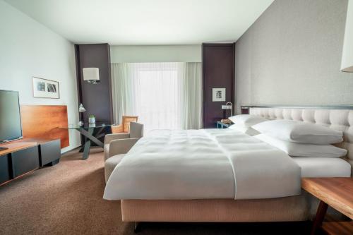 a bedroom with a large white bed and a television at Grand Hyatt Berlin in Berlin