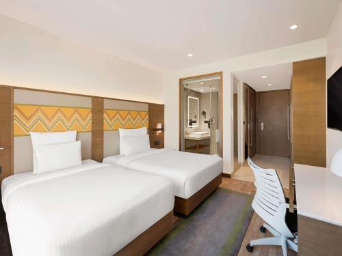 a hotel room with two beds and a desk and a desk at Novotel Guwahati GS Road in Guwahati