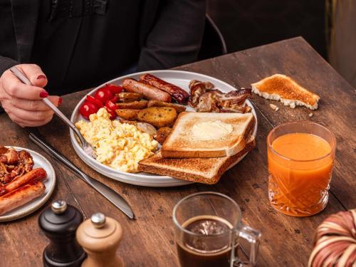 a table with a breakfast plate of eggs bacon and toast at Novotel Guwahati GS Road in Guwahati