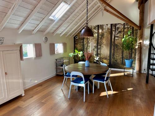a dining room with a wooden table and chairs at B&B Woudzicht in Oudeschoot