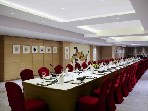 a conference room with a long table and red chairs at Grand Mercure Vadodara Surya Palace in Vadodara