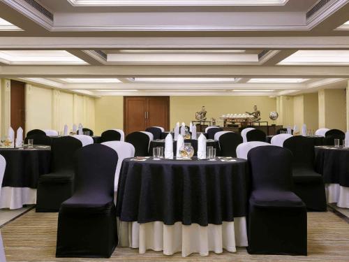 a room filled with tables and chairs with black and white at Grand Mercure Vadodara Surya Palace in Vadodara