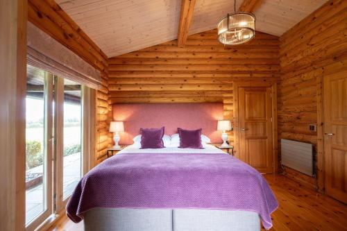 a bedroom with a large bed with purple sheets at Alborada in Constable Burton