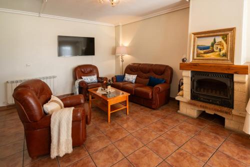 a living room with leather furniture and a fireplace at Hostal Valderas in Valderas