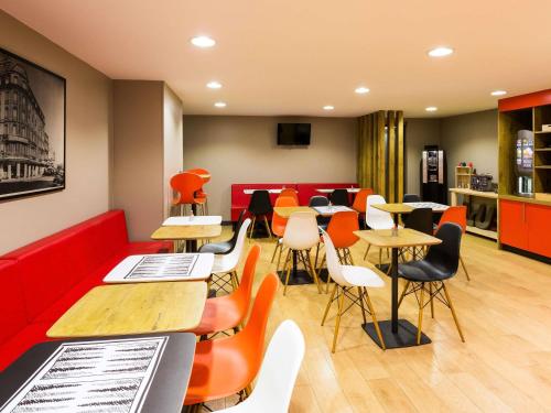 a restaurant with a red couch and tables and chairs at ibis Bordeaux Centre Gare Saint Jean Euratlantique in Bordeaux