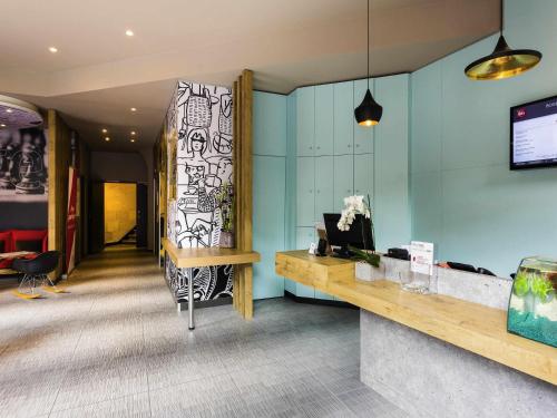 a lobby with a desk and a wall with a window at ibis Bordeaux Centre Gare Saint Jean Euratlantique in Bordeaux