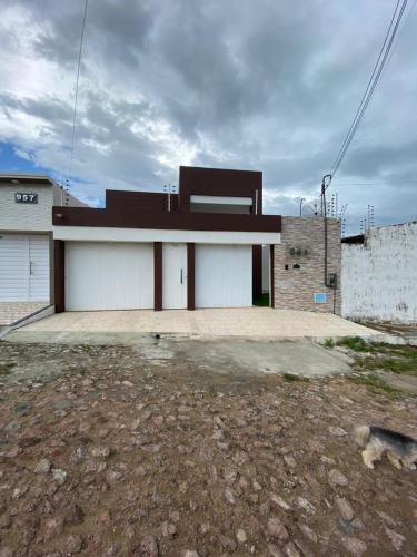 a building with a garage with a dog in front of it at Seller House II in Sobral