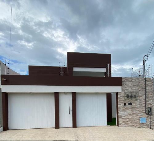a building with two white garage doors with a sky at Seller House II in Sobral