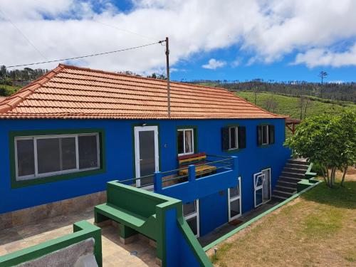 a blue house with a green bench in front of it at This Old House in Ponta do Pargo