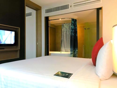 a bedroom with a bed with a tv and a bathroom at Mercure Kuala Lumpur Shaw Parade in Kuala Lumpur