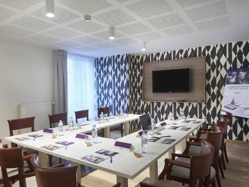 a conference room with a large table with chairs and a flat screen tv at Hotel Mercure Brest Centre Les Voyageurs in Brest