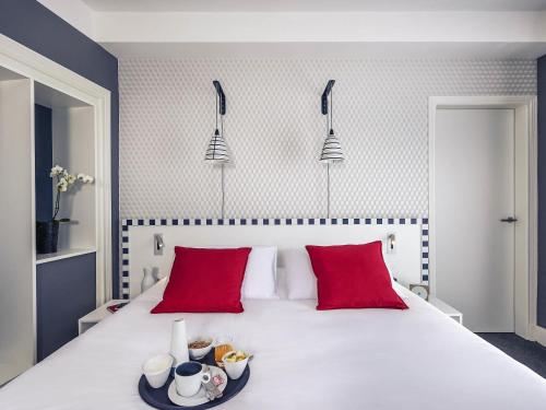 a bedroom with a large white bed with red pillows at Hotel Mercure Brest Centre Les Voyageurs in Brest