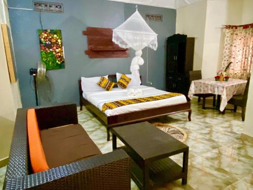 a bedroom with a bed with a table and chairs at Gorilla African Guest House in Entebbe