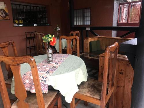 a dining room with a table and chairs with a vase of flowers at Gorilla African Guest House in Entebbe