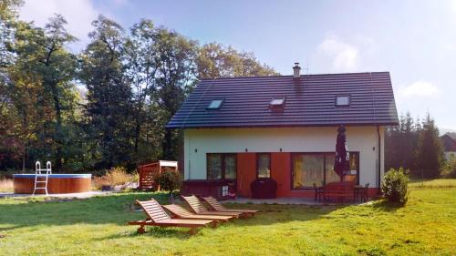 a small house with lounge chairs in a yard at Dům v srdci Beskyd - Morávka - 6 pokojů in Morávka