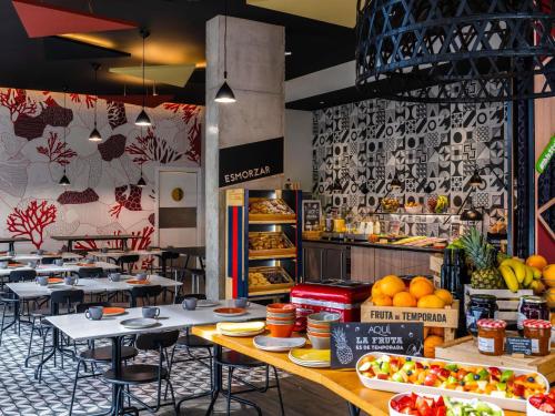 a restaurant with tables and chairs and fruits and vegetables at ibis Styles Barcelona City Bogatell in Barcelona