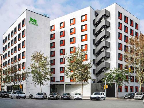 two white buildings with cars parked in front of them at ibis Styles Barcelona City Bogatell in Barcelona