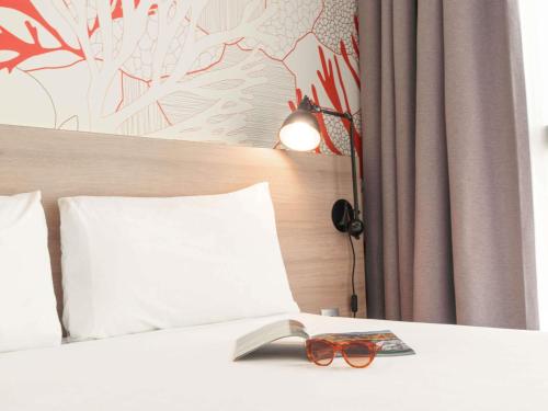 a pair of glasses sitting on top of a bed at ibis Styles Barcelona City Bogatell in Barcelona