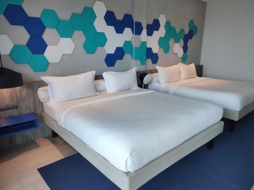 two beds are in a room with a wall at ibis Styles Batam Nagoya in Nagoya