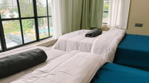 two beds sitting next to a window in a bedroom at Batu Caves Cozy 2 Storey House with Free Netflix in Batu Caves