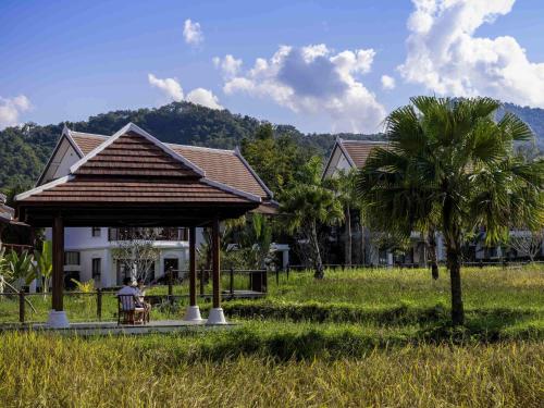 a man sitting in a gazebo in front of a house at Pullman Luang Prabang in Luang Prabang