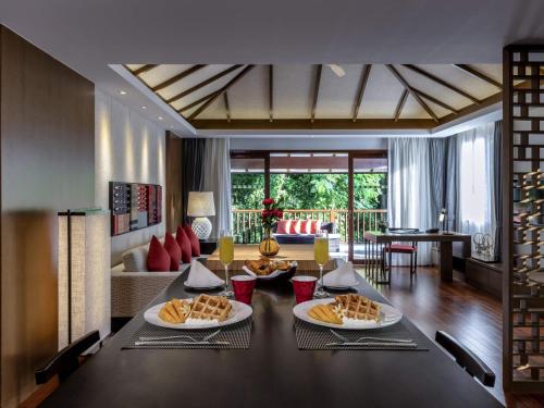a dining room with a table with food on it at Pullman Luang Prabang in Luang Prabang