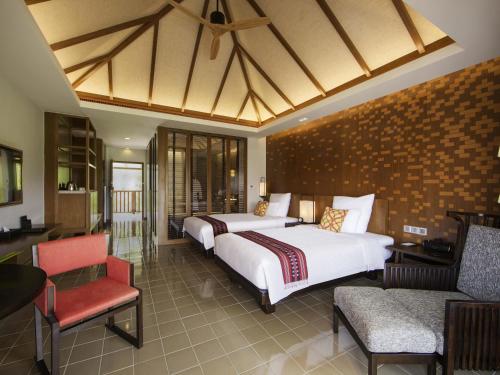 a hotel room with two beds and a chair at Pullman Luang Prabang in Luang Prabang
