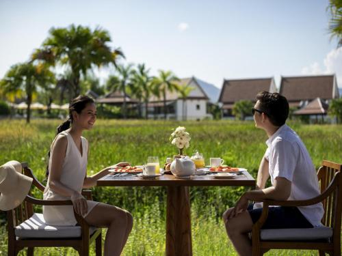a man and a woman sitting at a table at Pullman Luang Prabang in Luang Prabang