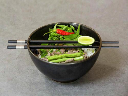 a bowl of food with chopsticks and vegetables at Pullman Luang Prabang in Luang Prabang