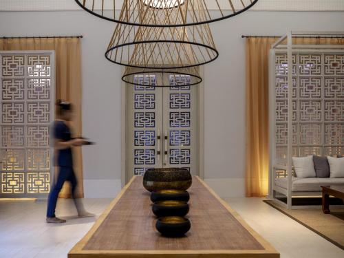 a person walking in a living room with a chandelier at Pullman Luang Prabang in Luang Prabang
