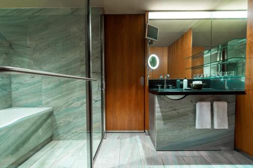 a bathroom with a shower and a sink and a tub at Grand Hyatt Berlin in Berlin