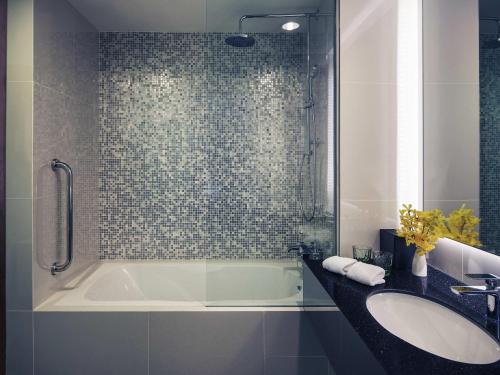 a bathroom with a bath tub and a sink at Mercure Yangon Kaba Aye in Yangon