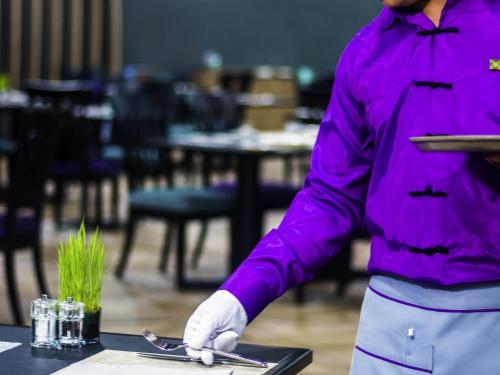 a person in a purple shirt holding a knife on a table at Mercure Yangon Kaba Aye in Yangon